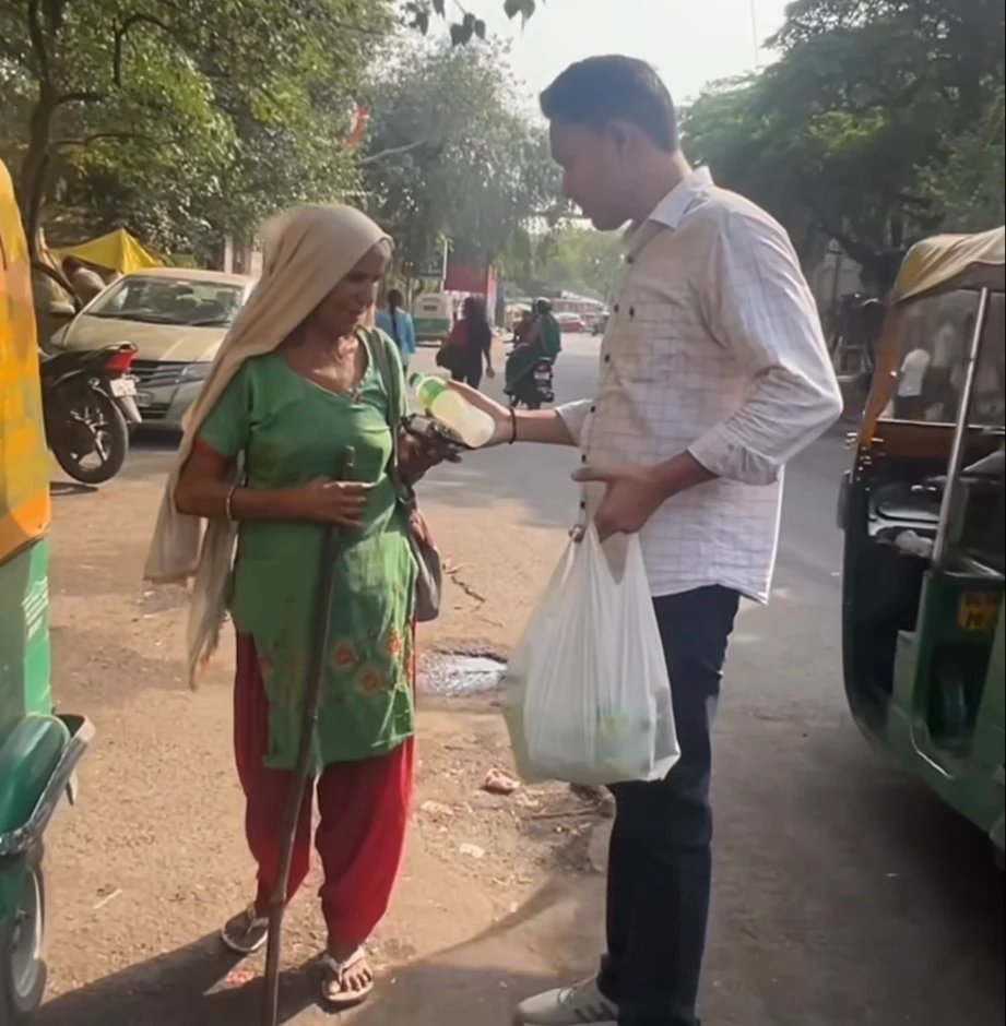 Our volunteer giving a drink to an elderly woman on the street