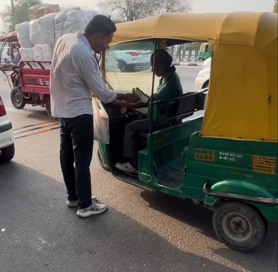 Our volunteer handing a drink to an auto-rickshaw driver