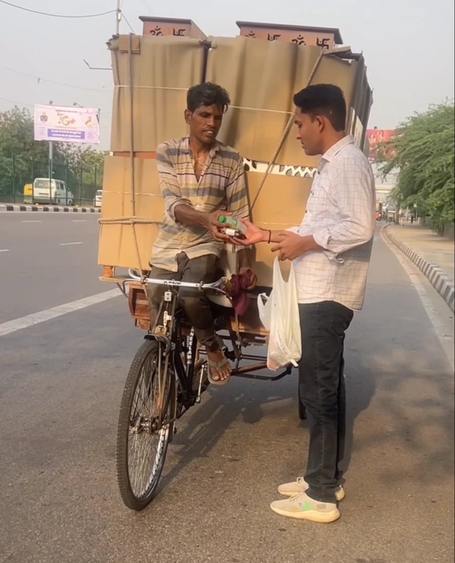 Our volunteer giving a drink to a rickshaw puller carrying a heavy load