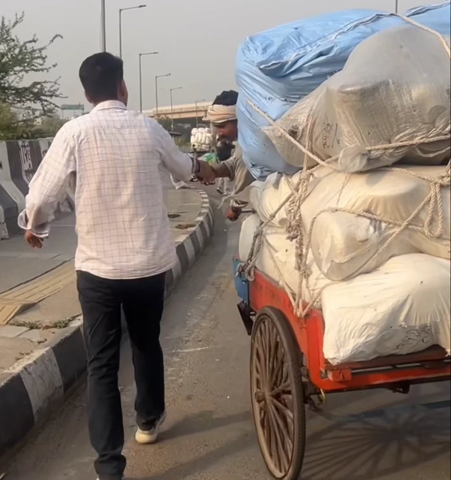 Our volunteer handing a drink to a cart puller on a busy road